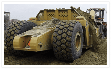 Pulldozer scraper operating in muddy field conditions